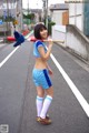 A woman in a blue and white uniform holding a baseball bat.