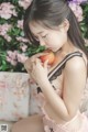 A woman in a pink lingerie holding an apple.