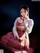 A woman in a pink kimono sitting on a bench.