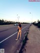 A naked woman walking down the middle of the road.