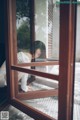 A woman laying on the ground looking out of a window.