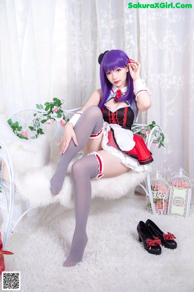 A woman in a maid outfit sitting on a white chair.