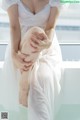 A woman in a white dress sitting on a window sill.