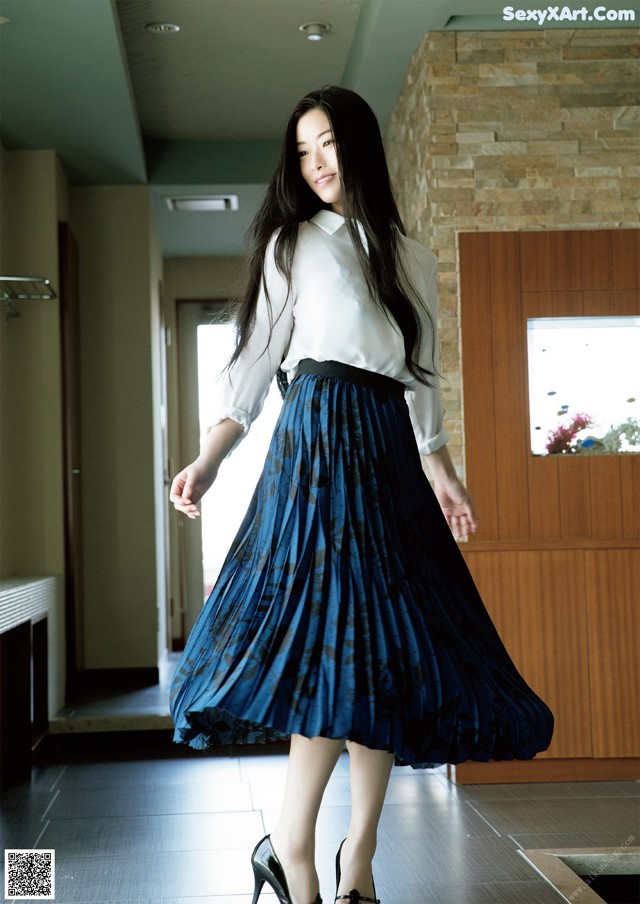 A woman in a white shirt and blue pleated skirt.